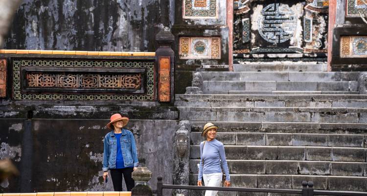 Deux femmes debout au bas d'anciens escaliers de pierre avec des éléments décoratifs.