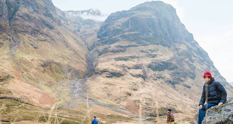 Excursionistas explorando laderas montañosas escarpadas y pedregal en la región de Glencoe en Escocia