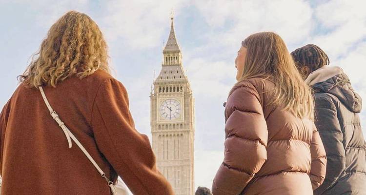Trois jeunes voyageurs regardent vers Big Ben lors d'une belle journée à Londres.