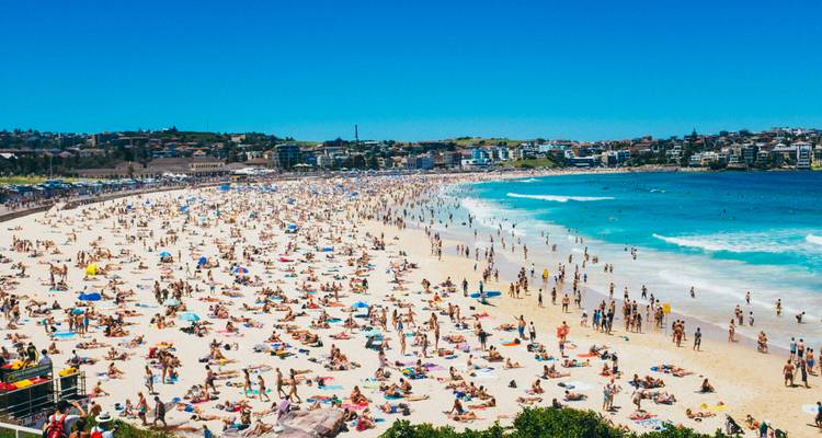 Plage de Bondi bondée avec des gens profitant du soleil et de l'eau.