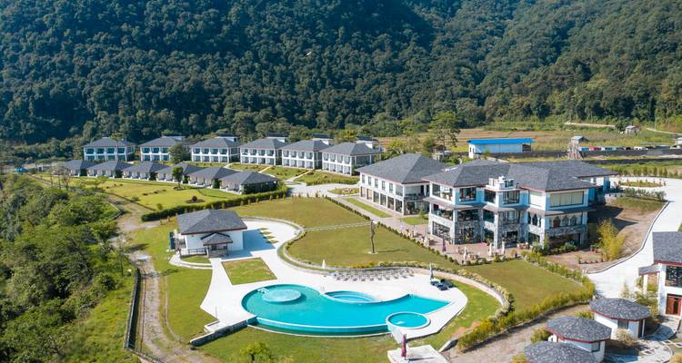 Vista aérea de un resort con piscina y exuberante vegetación.