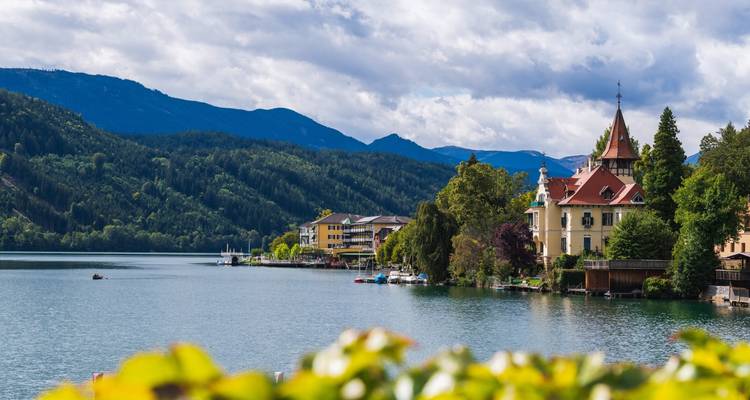 Vista panorámica junto al lago con edificios coloridos y montañas.