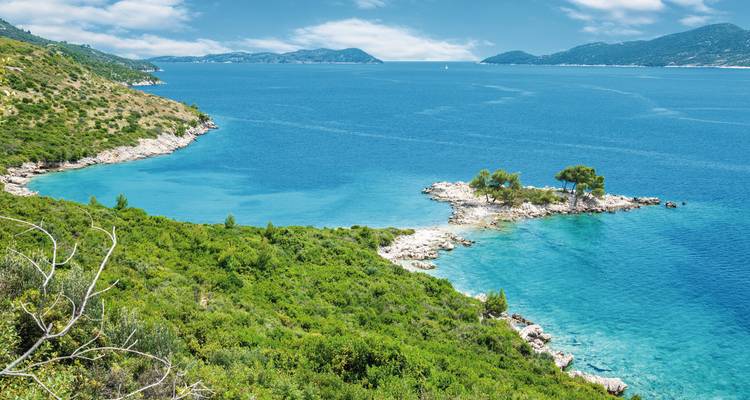Isolated coastal landscape with turquoise waters and green hills.