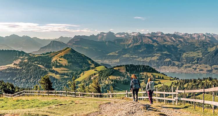 Zwei Wanderer auf einem Wanderweg mit Blick auf ein Bergpanorama.