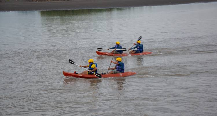 Groupe de kayakistes pagayant sur une rivière calme.