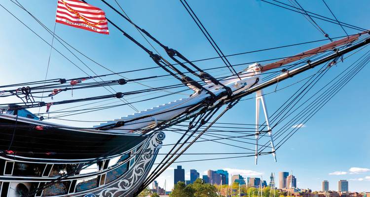 Historic sailing ship with Boston city skyline in the background.