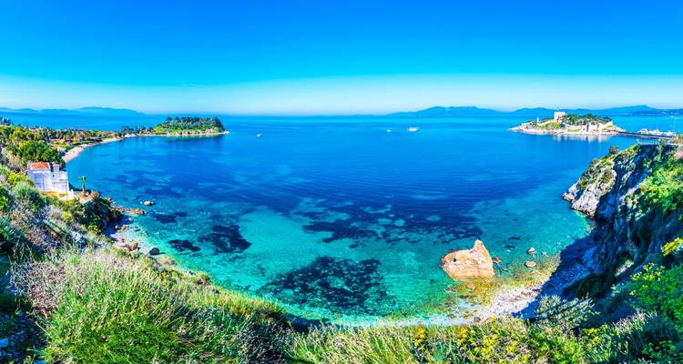 Une belle vue côtière avec des eaux bleues claires et une petite île avec une forteresse.