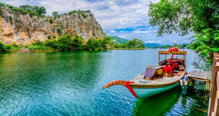 Traditional wooden boat on a scenic river with cliffs.