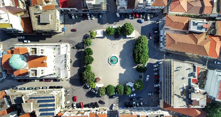 Vue aérienne d'une place de ville avec une fontaine et des arbres.