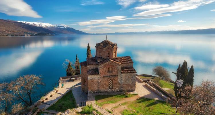 Iglesia en un acantilado con vista a un lago tranquilo.