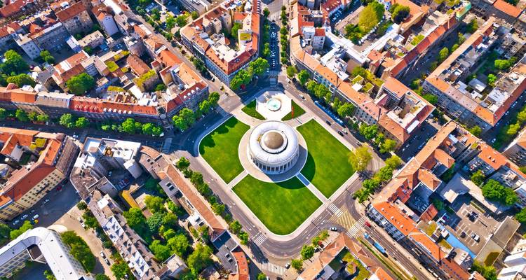 Vue aérienne d'un bâtiment rond entouré de verdure dans un paysage urbain.