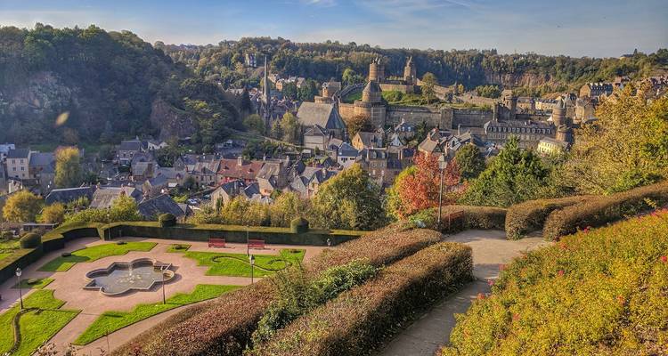 A hilltop view of a village with a backdrop of lush green woods and scenic landscapes.