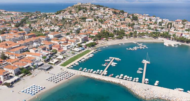 Aerial view of a coastal town with marina and blue sea.