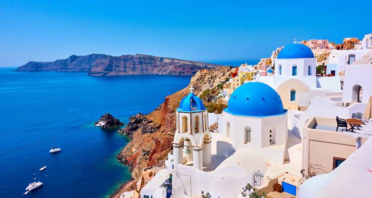 Iconic white buildings with blue domes overlooking the sea and a rocky coastline.