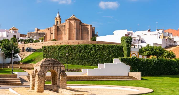Une église historique avec des jardins devant, sous un ciel bleu.