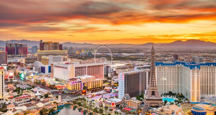 Colorful sunset over Las Vegas Strip showing hotels, High Roller and distant mountains.