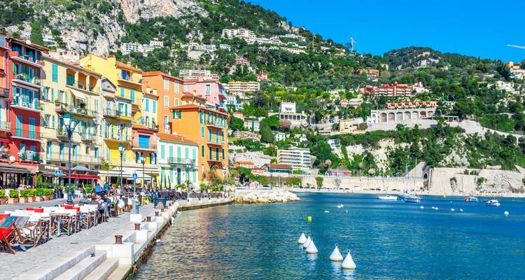 Coastal town with colorful buildings and people dining along the waterfront.