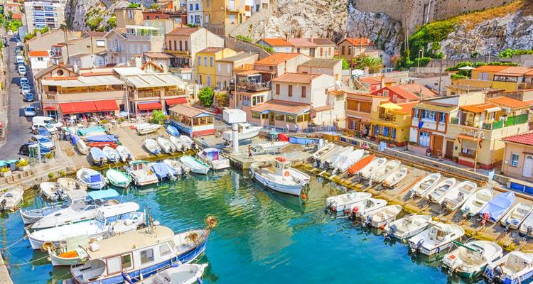Sunny harbor with boats docked alongside colorful seaside buildings.