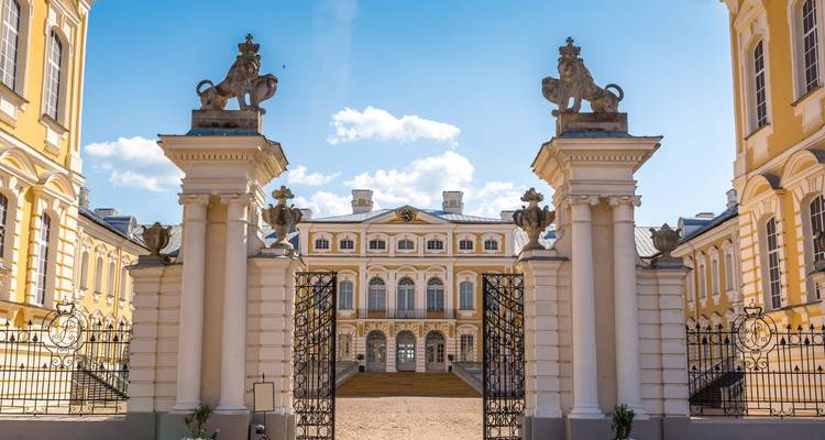 Luxurious palace entrance with sculptures and ornamental gates.