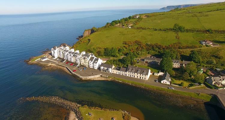 Vue aérienne d'un village côtier avec des maisons au bord de la mer.