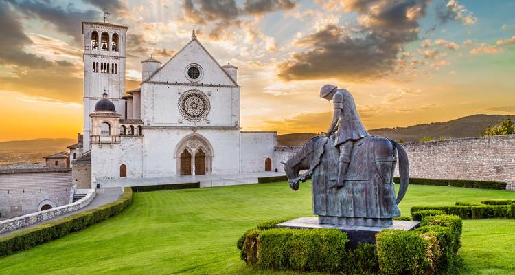 Una estatua frente a una iglesia conocida durante la puesta de sol.