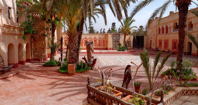 Courtyard enclosed by arches and adorned with palm trees.