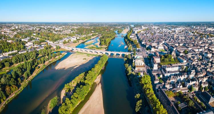Vista aérea de un río serpenteando a través de una gran ciudad, con puentes antiguos visibles.