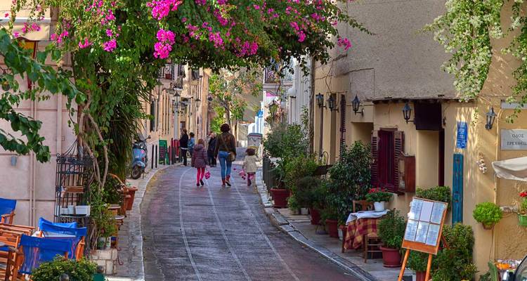 Charming street in Athens with people walking under blooming bougainvillea.