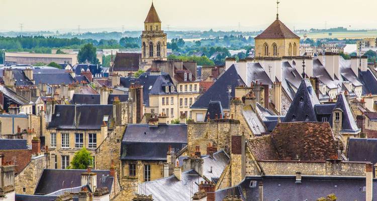 City rooftops with church towers and a distant landscape.