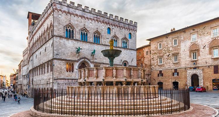 Plaza histórica con fuente y palacio medieval en Perugia.