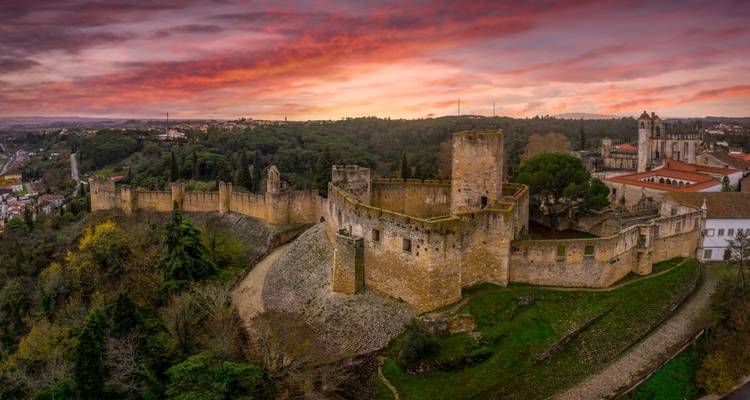 Zonsondergang boven een historisch kasteel en omliggend landschap.