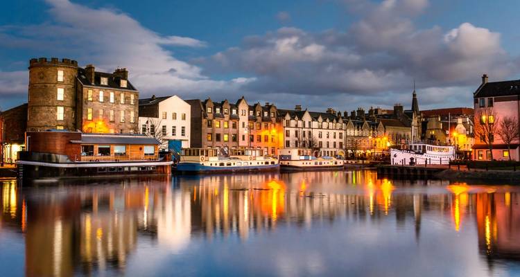 Bâtiments colorés au bord de l'eau illuminés la nuit.