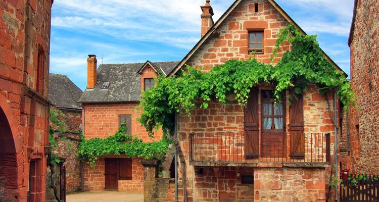 Casas de piedra antiguas con exuberantes enredaderas verdes en un pueblo pintoresco.