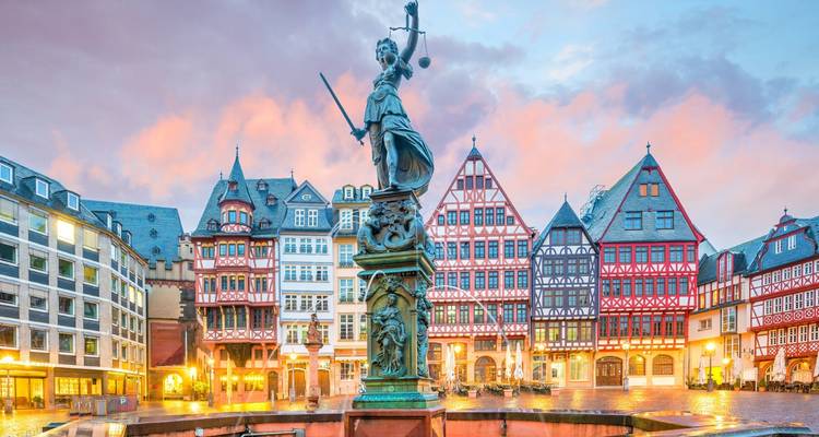 Kleurrijke traditionele gebouwen met een historische fontein bij zonsondergang.