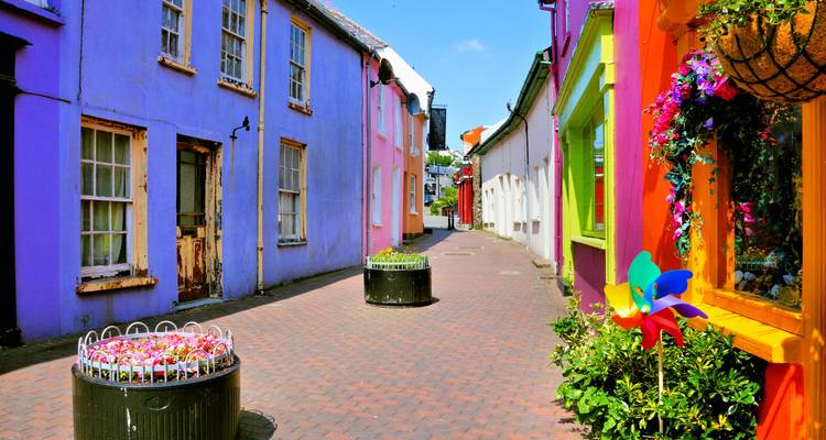 Rue étroite aux couleurs vives avec des pots de fleurs et un ciel bleu clair.