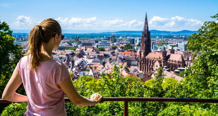 Jonge toerist die uitkijkt over het stadslandschap van Freiburg vanaf een heuveltopterras.