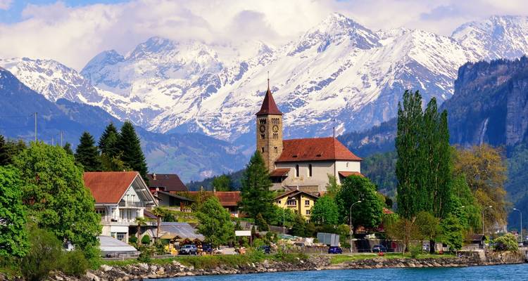 Un petit village au bord du lac encadré par de majestueuses montagnes enneigées.