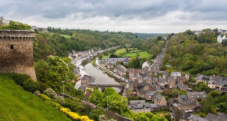 Vue panoramique d'une vallée fluviale avec des structures médiévales et une végétation luxuriante.