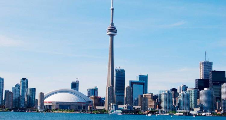 Iconic Toronto skyline featuring CN Tower and Rogers Centre viewed across shimmering lake water.