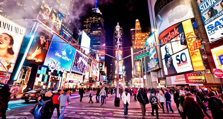 Vibrant night scene of Times Square filled with billboards, lights and crowds of pedestrians.
