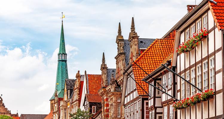 Street with timber-framed buildings and red-roofed spires.