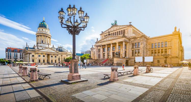 Grande place publique avec des bâtiments historiques et une église à dôme.