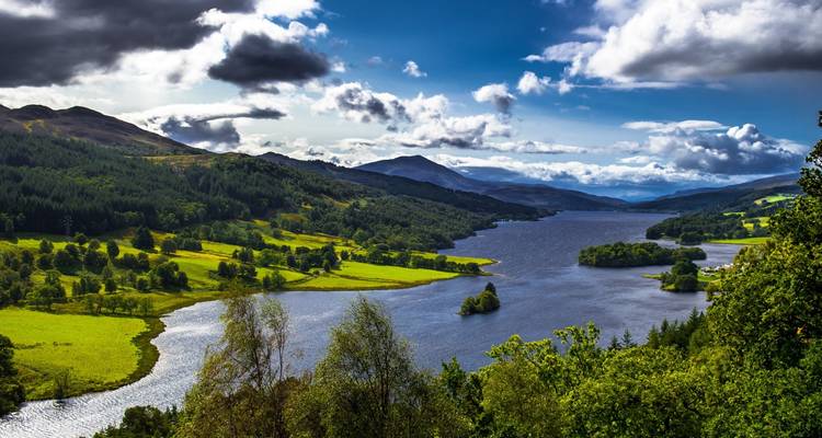 Paisaje escénico que presenta un lago rodeado de colinas verdes y bosques.