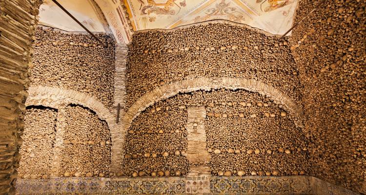 Interior room lined with walls of bones and skulls.