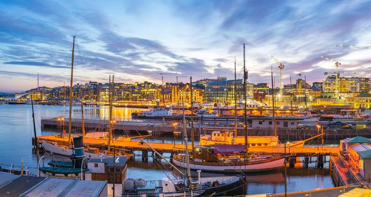 Port d'Oslo au crépuscule avec bateaux et bâtiments illuminés.