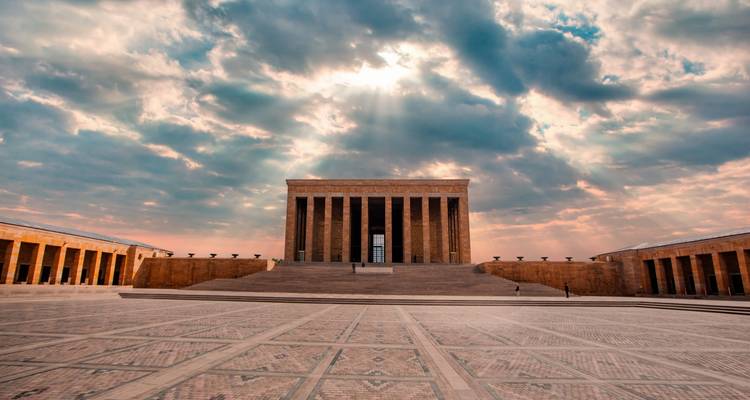 Un grand bâtiment imposant avec des colonnes sous un ciel nuageux.