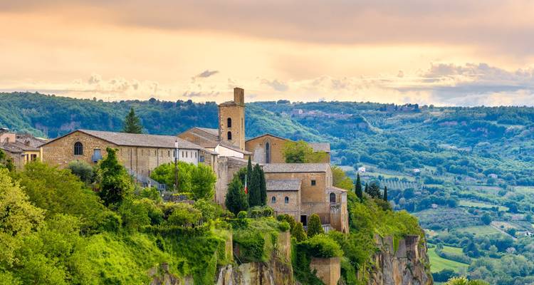 Vista panorámica de un edificio histórico en la cima de una colina verde y frondosa.