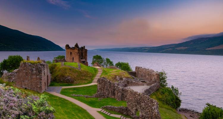 Ruines historiques au bord d'un lac au coucher du soleil.