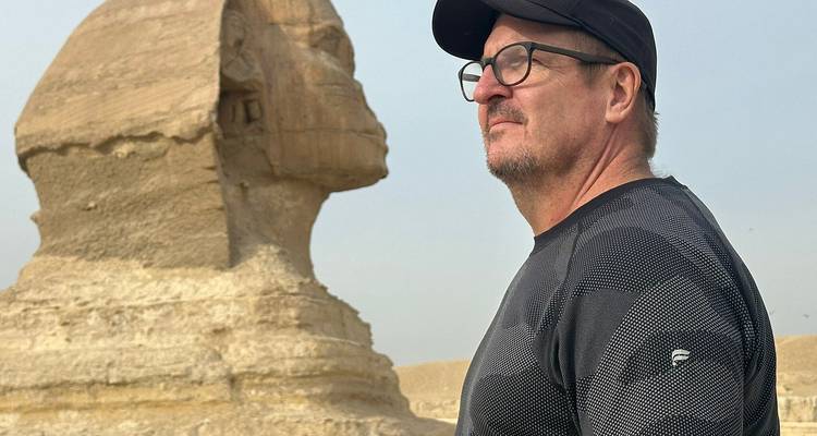 Hombre posando junto a la estatua de la Esfinge.