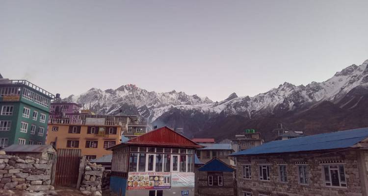 Village de montagne avec des maisons colorées et des sommets enneigés au loin.